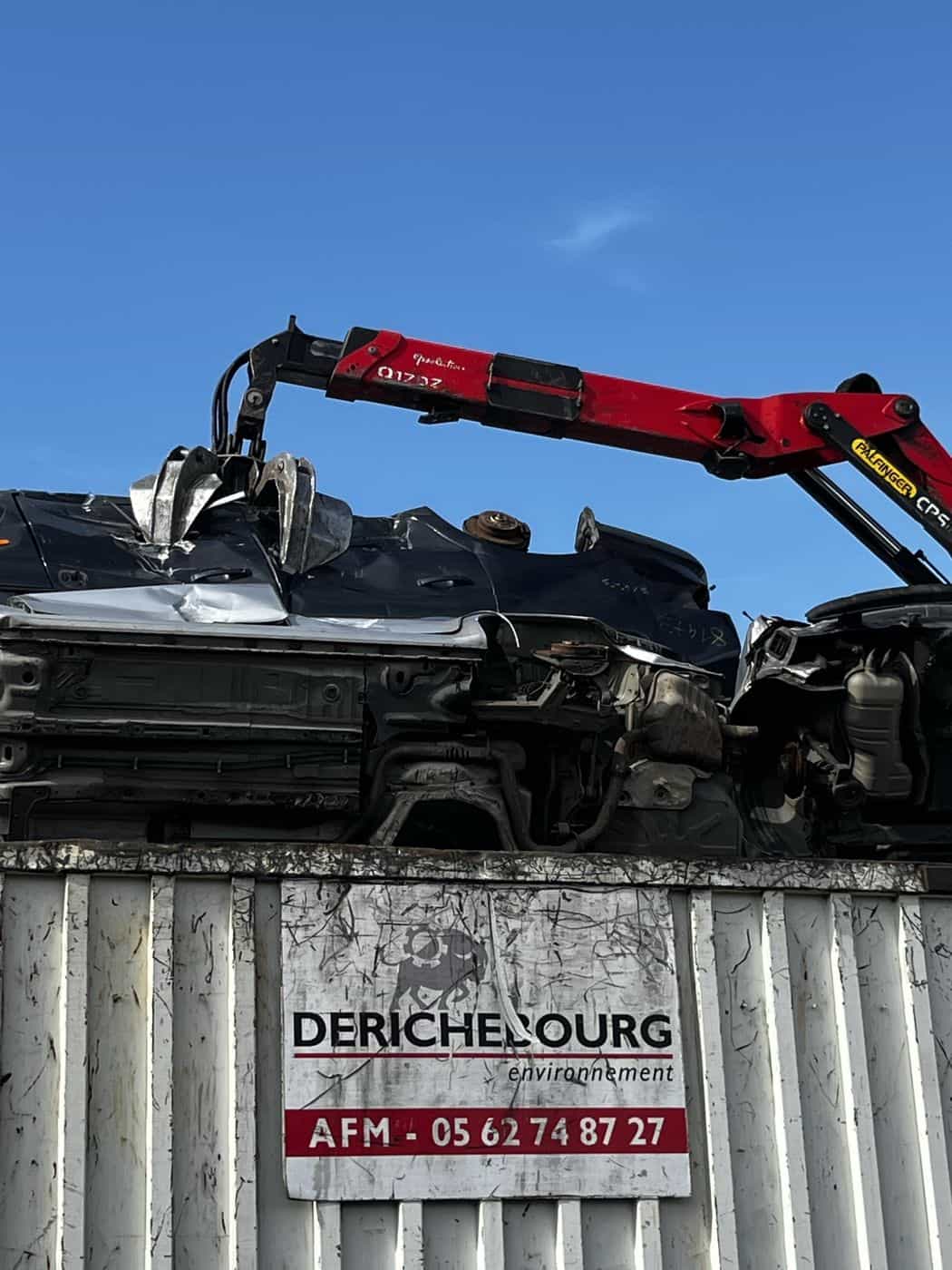 Grue de manutention soulevant un véhicule hors d'usage